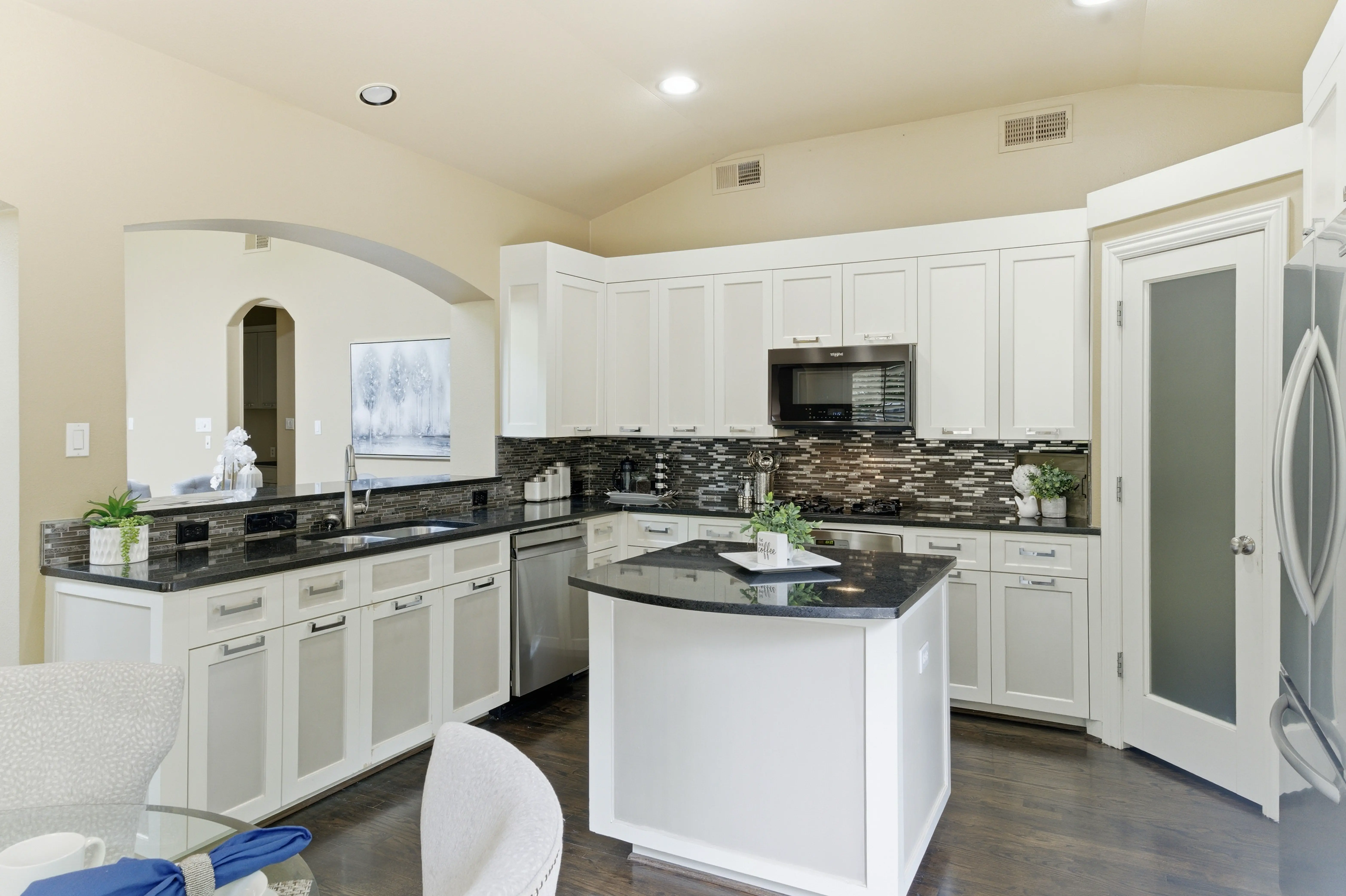 Kitchen with white cabinetry, granite countertops, and mosaic backsplash